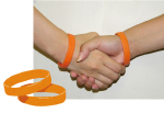 「オレンジリング」を手首に付けて握手をしている写真