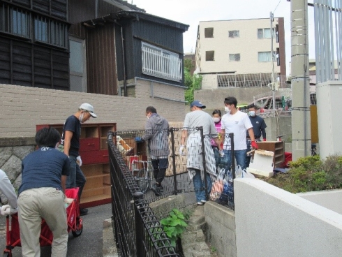 車が通ることの出来ない道路から荷物を運んでいる様子の写真