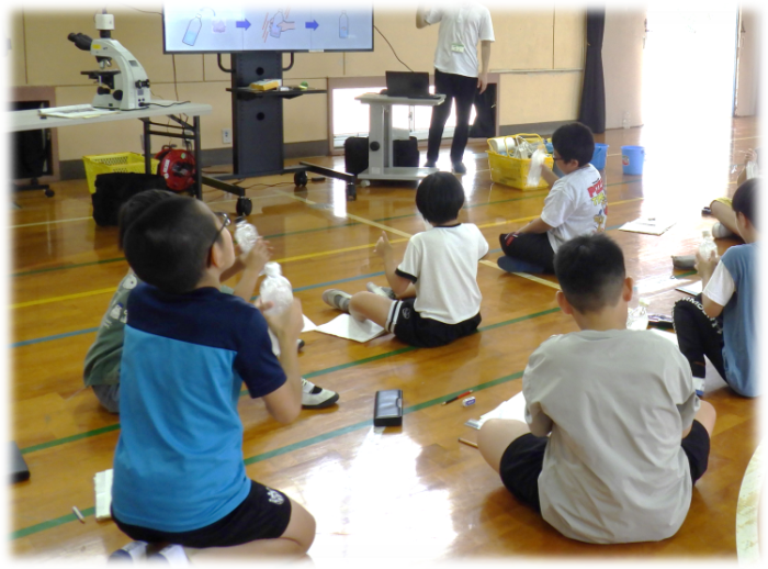 ペットボトルを使用した水に溶けるものを調べる実験を行う子どもたちの写真